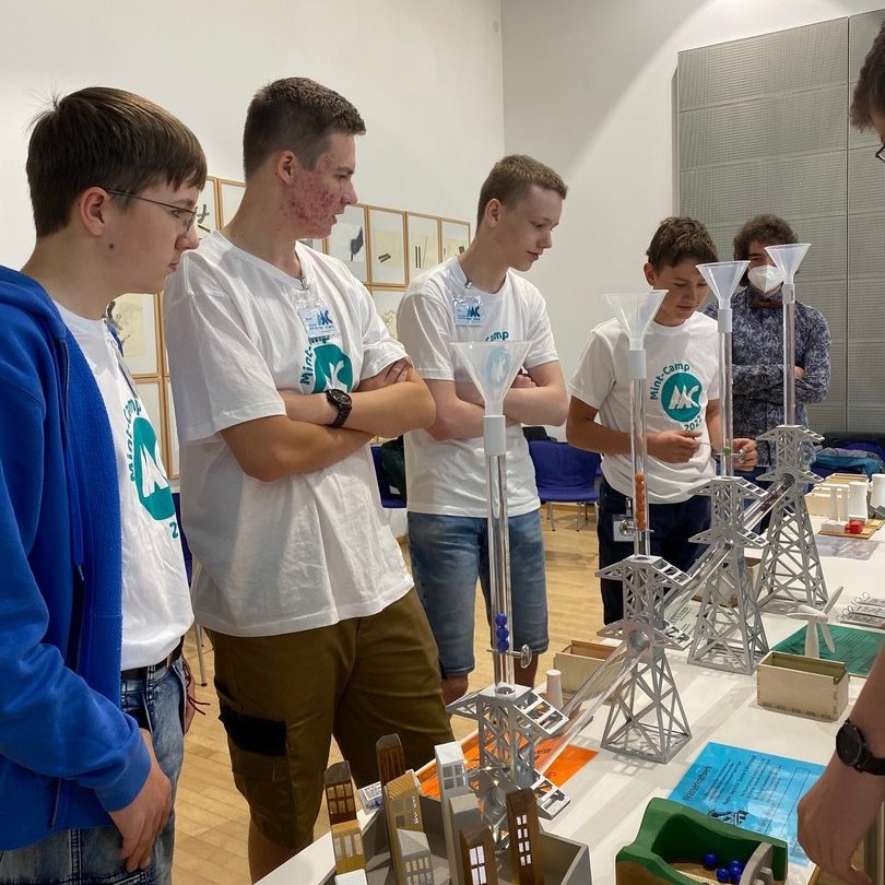 Mehrere Jugendliche betrachten ein Versuchsaufbau einer Energieanlage